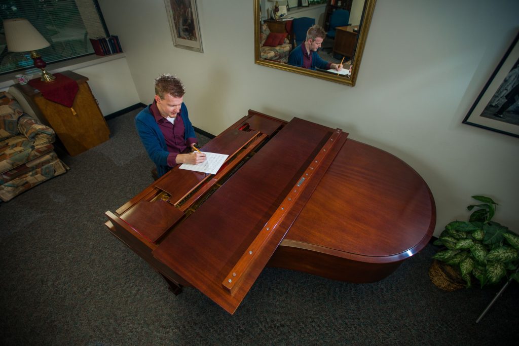 A music student composing at a grand piano.