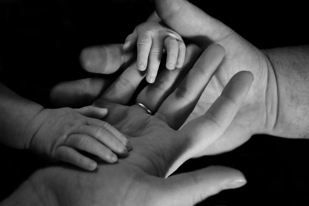 A man's hands holding a baby's hands