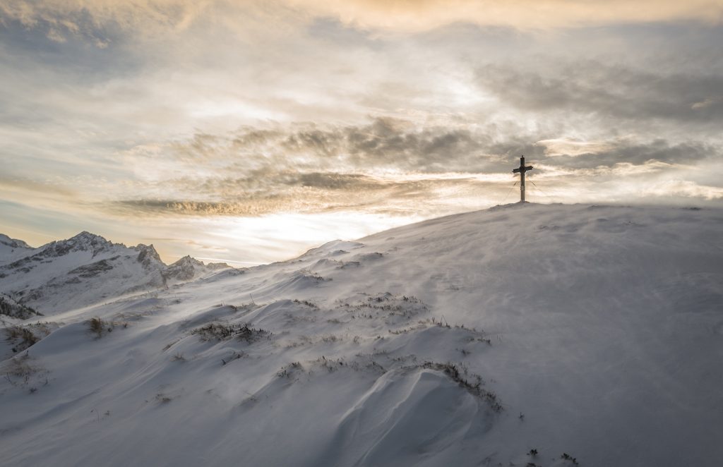 Snowy cliff with a cross at the top