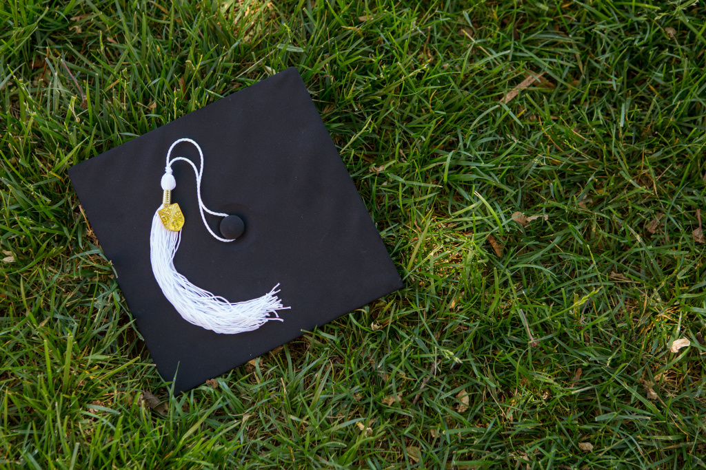 Graduation cap lying in the grass with BJU shield on tassel