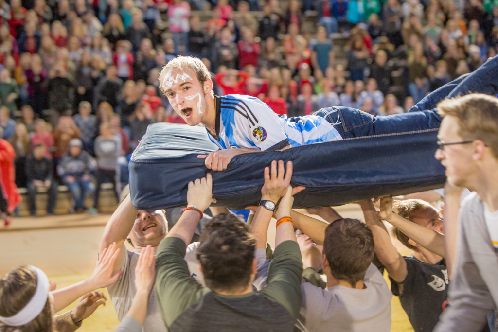Students passing a student in a mattress race in Alumni Stadium during Bruins Daze