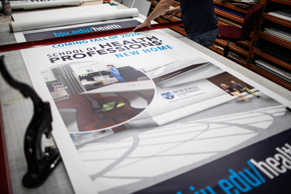 X-stand banners announcing the School of Health Professions' new home come off the printer