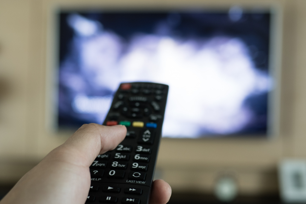 Hand with remote pointed at television