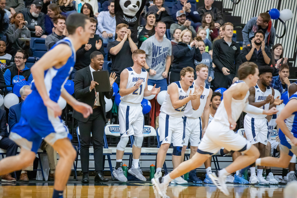 The Bruins men basketball team cheer their teammates as they play against the PCC Eagles