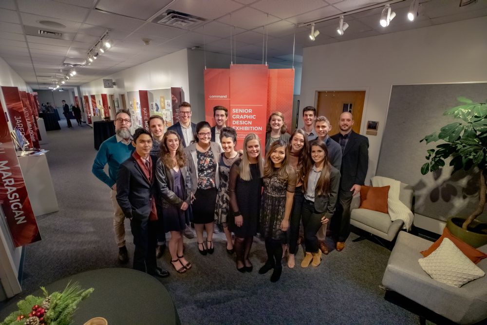 Graphic design seniors stand at the entrance to their exhibition in the Sargent Art Building (Photo by Hal Cook)