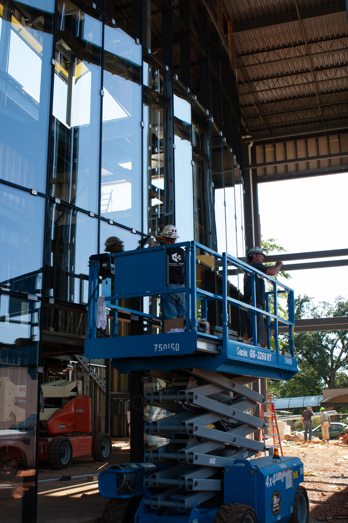 Construction workers carefully install the large glass panes that make up the front wall of the lobby