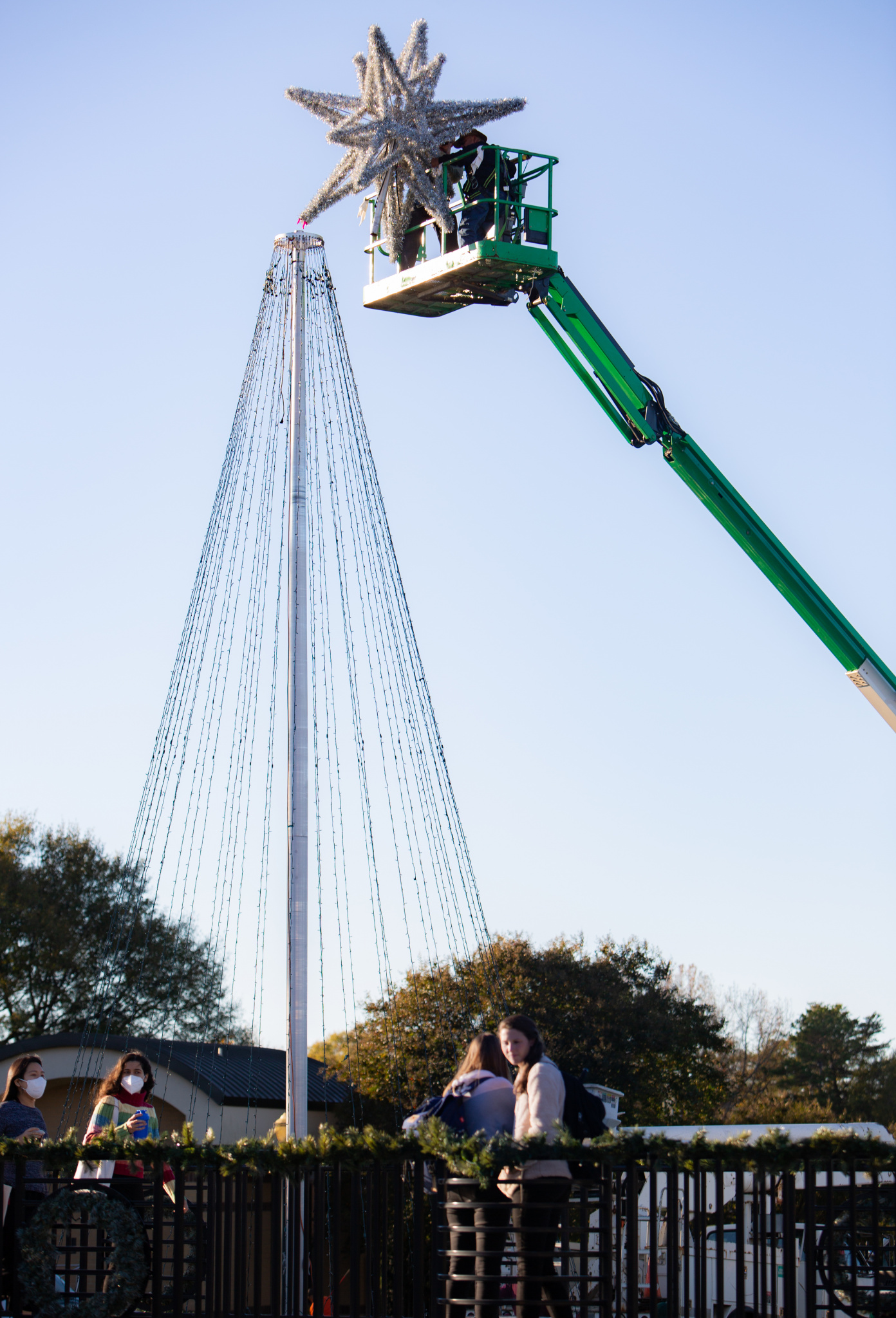 A worker in a bucket truck attaches the star to the light tree on front campus (Photo by Taylor Caldwell)
