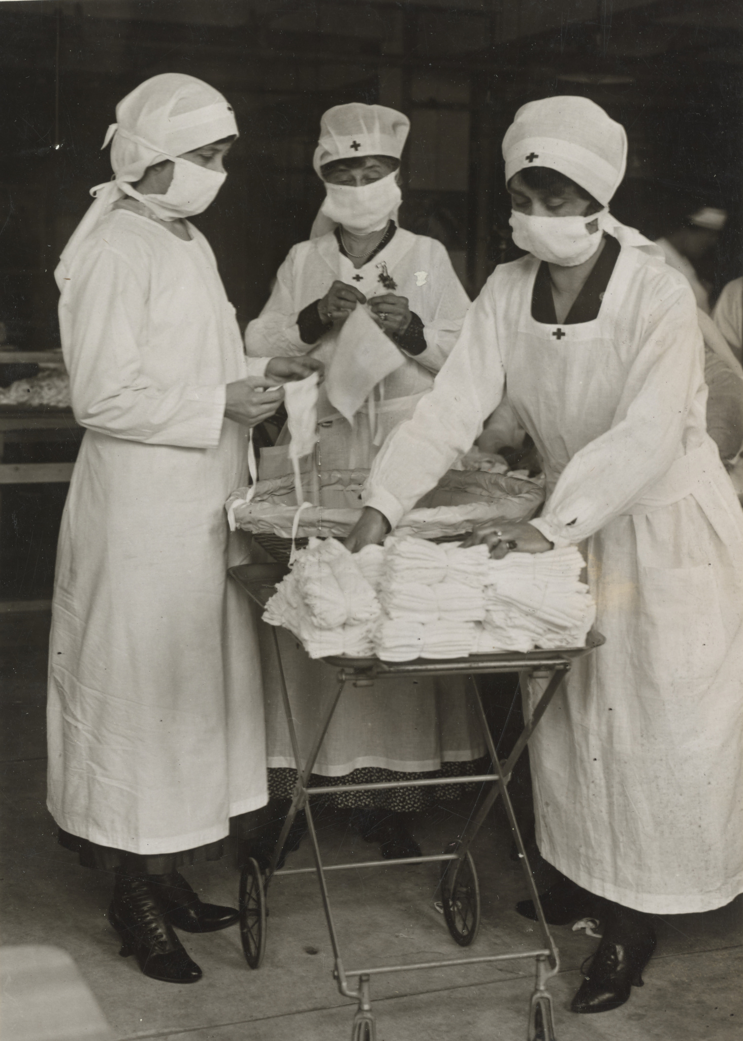 Red Cross workers of Boston, Massachusetts, removing bundles of masks for American Soldiers from table where other women are busily engaged in making them