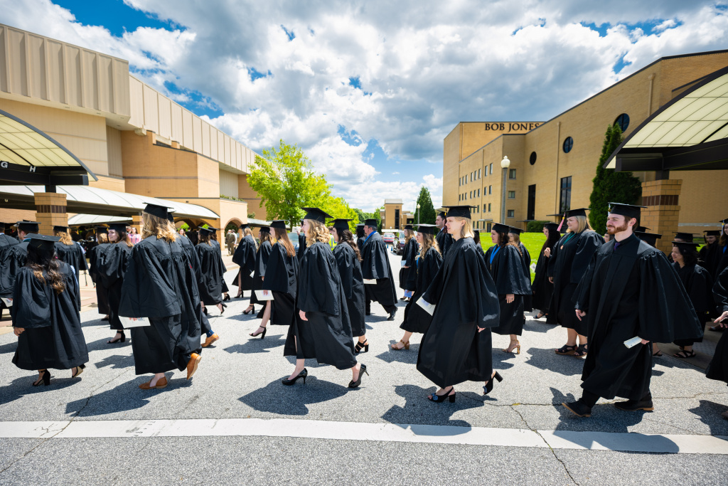 Graduates walk across the road between Rodeheaver Auditorium and Founder's Memorial Amphitorium to begin the commencement ceremony